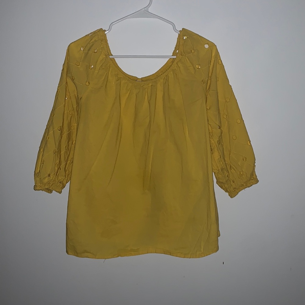This very unique top is a beautiful yellow with small cut outs in the sleeve.